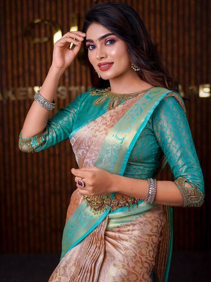 This model is wearing a unique beige and teal saree. The drape is styled to highlight the unusual color combination and the intricate blouse neckline.