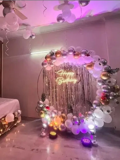 A duplicate of the bedroom birthday setup, showing the circular arch, fringe backdrop, and neon sign under purple lighting.
