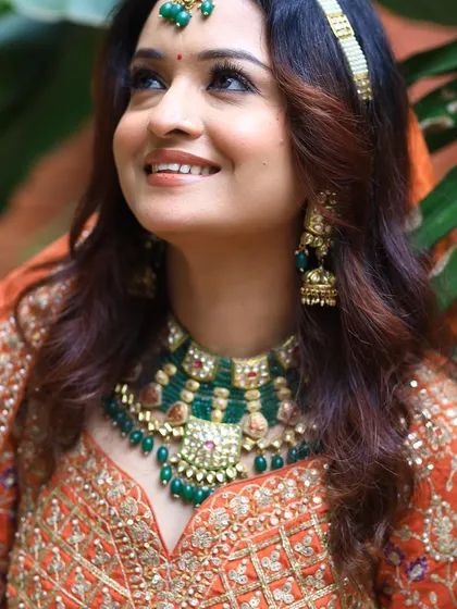 A close-up on the beautiful smile and the intricate green jewelry.