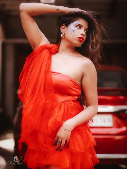 A more expressive and dynamic pose, with a hand in her hair. The creative makeup adds an artistic, edgy touch to the look.