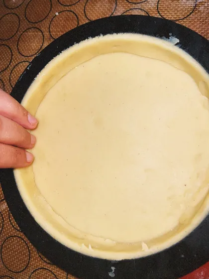 Carefully lining a tart ring with the handmade dough. This step is crucial for creating a perfect, crisp tart shell.