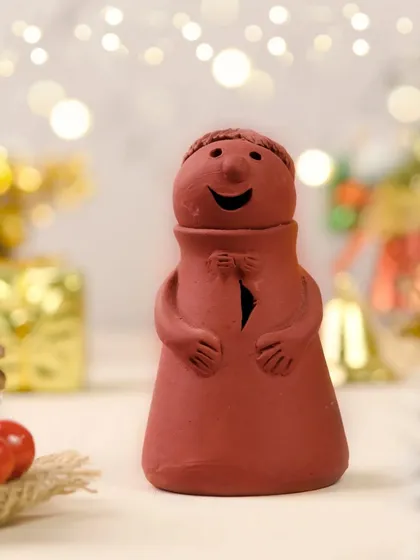 Simple, rustic, and full of holiday cheer. This small terracotta figurine is styled with festive lights and natural elements like pinecones to create a warm and charming Christmas photo.