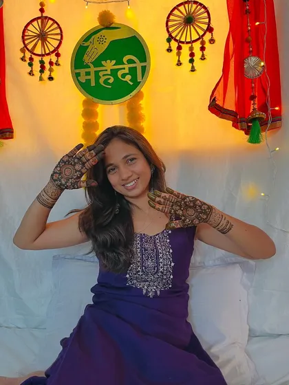 Posing in front of the mehendi decor, feeling happy and festive.