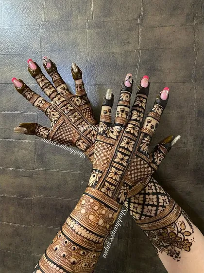 A fun pose showing off the full back-of-hand bridal mehndi. The intricate patterns look stunning when displayed like this.