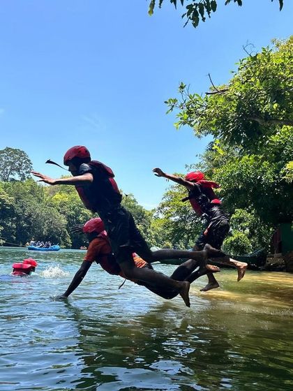 A group of campers leap into the water together, a perfect picture of shared joy and adventure.