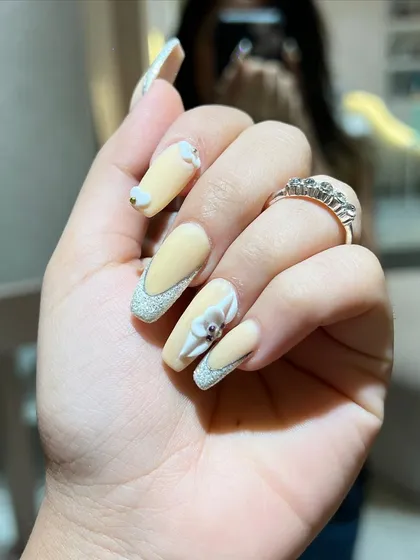 A soft yellow base with glittery French tips and delicate 3D white flowers. This set is perfect for a sunny day.
