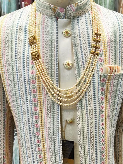 This open sherwani features a unique multi-color striped pattern, offering a fresh and modern take on groomswear. The look is completed with a multi-layered pearl necklace, perfect for an engagement or sangeet.