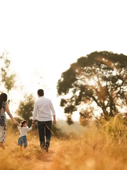 A family walking hand-in-hand through a field during golden hour. This style creates a timeless, storybook feel for your family portraits.