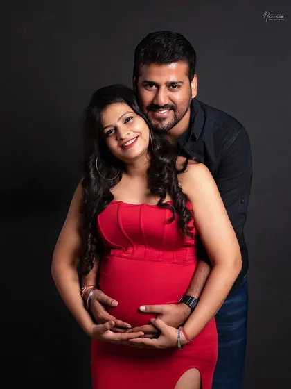 A warm embrace from behind, with both parents' hands on the baby bump. This pose creates a wonderful feeling of protection and unity as they look forward to meeting their baby.