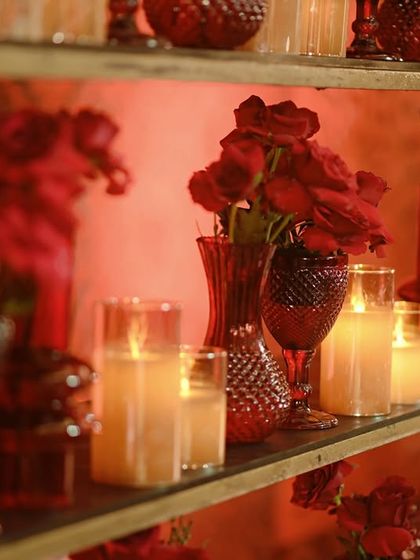 A close-up of the glowing bar back shelves, where red vases and candles create a mesmerizing display of light and color.