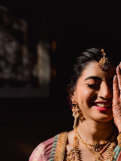 A beautiful, artistic shot of Nidhi during her Muhurtham. The play of light and shadow highlights her glowing skin and joyful expression.