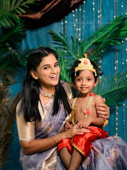 A mother and her son, dressed as little Krishna, share a happy moment during a Janmashtami photoshoot. This image beautifully combines a festive theme with the mother-son bond.