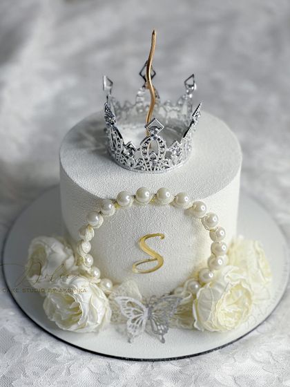 A "Snow White" inspired mini cake. This design has a white velvet spray finish and is decorated with a silver crown, pearls, and delicate wafer paper flowers.