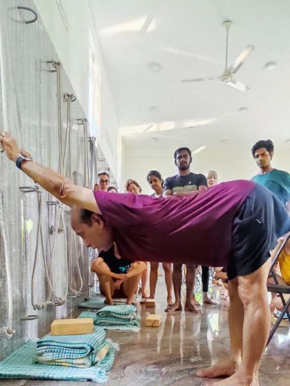 A standing forward bend using wall ropes.