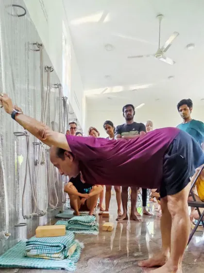 A standing forward bend using wall ropes.