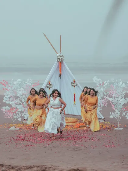 The bride and her squad celebrating with pure energy during a beachside Haldi ceremony. This photo is all about the joy, friendship, and vibrant fun that surrounds a wedding.