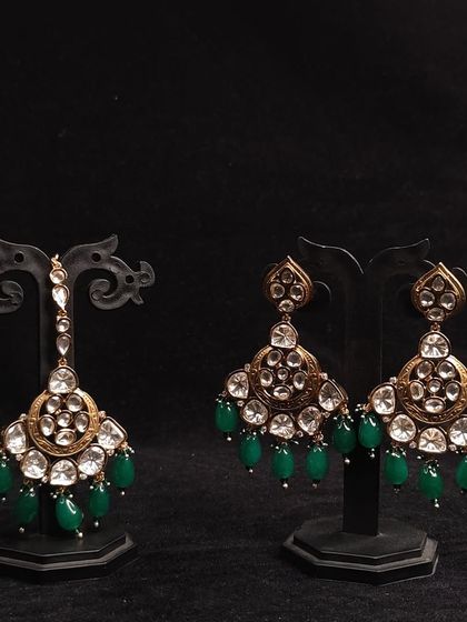 A set of Polki earrings and a matching maang tikka with green bead drops. Rent these to complete your traditional look.