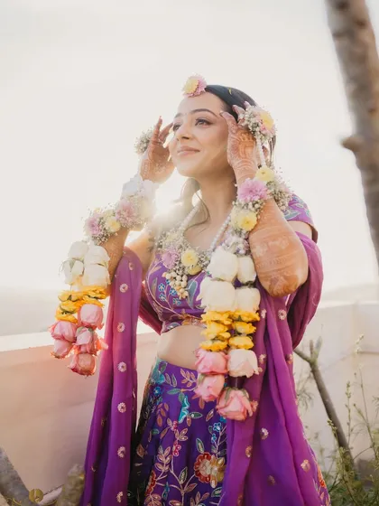 The bride, Arushi, glowing in the sunlight, adorned with beautiful floral jewelry for her haldi ceremony. This portrait captures her radiance and the beauty of the mountain setting.