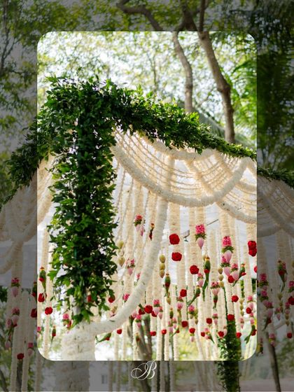 A close-up of the mandap corner, where lush green foliage wraps around the pillar and meets the scalloped tuberose garlands. This detail shows how we merge natural elements with traditional floral work.