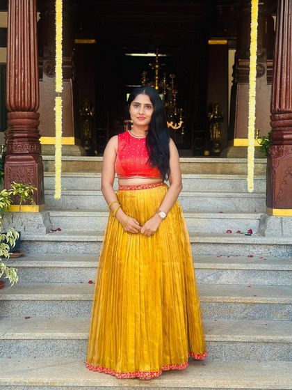 A beautiful Kanchivaram tissue pleated skirt in mustard yellow, paired with a contrasting red hand-embroidered silk crop top. This is a modern way to wear traditional fabrics.