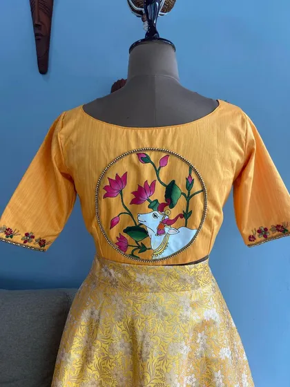 A custom-designed yellow blouse featuring a hand-painted Pichwai art motif on the back. This piece combines traditional Indian art with modern tailoring, a specialty I offer for clients seeking truly unique ethnic wear.