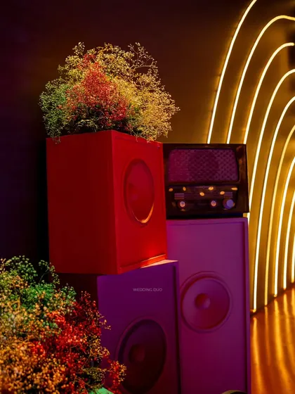 A close-up of the eclectic details on our futuristic sangeet stage, where colorful, retro-style speakers are used as pedestals for floral arrangements.
