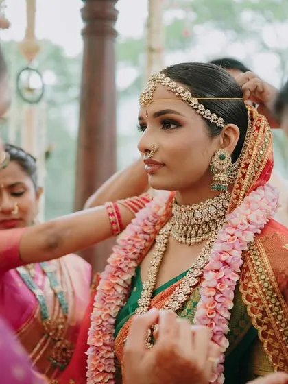 The bride getting ready with her family during her Mahuratham. This shot shows a close-up of the detailed eye makeup and the matha patti, key elements of a traditional South Indian bridal look.