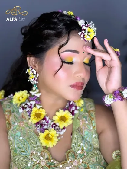 A close-up of the Haldi makeup, featuring a pop of yellow eyeshadow and rosy cheeks, perfectly complementing the floral jewelry.