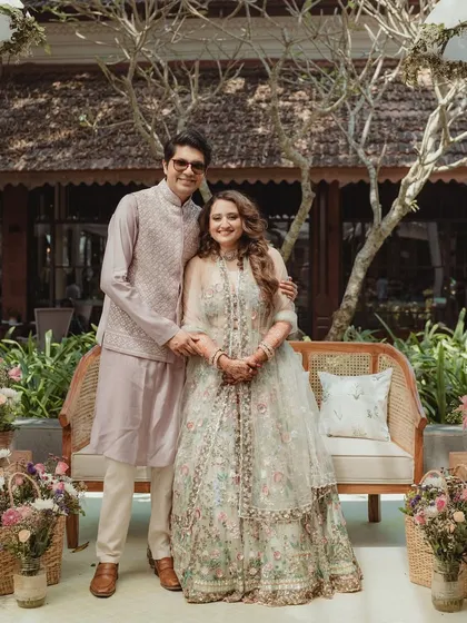 A full-length portrait of the couple at their Goa Mehendi. Their pastel outfits perfectly complement the soft, sun-drenched aesthetic of the decor.