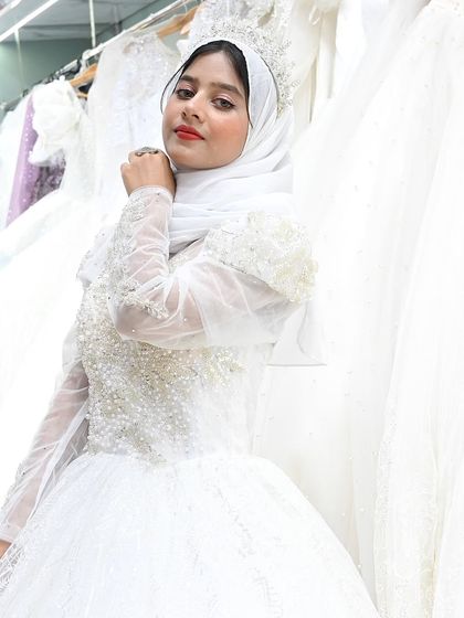 A close-up portrait of a bride in her custom gown, featuring a fully beaded bodice and illusion sleeves. Her confident expression says it all.