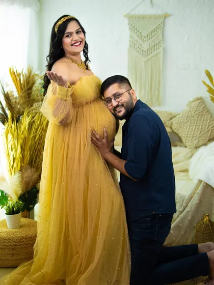 We love capturing the shared joy of expecting parents. This classic pose, with the partner listening to the baby bump, is a heartwarming way to document your connection and excitement. This shot was taken in our boho-chic studio setup.