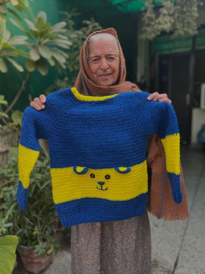 A cute and classic baby sweater in blue and yellow. The simple design is elevated with a sweet bear face stitched right into the center stripe, making it an adorable and cozy choice for your little cub.
