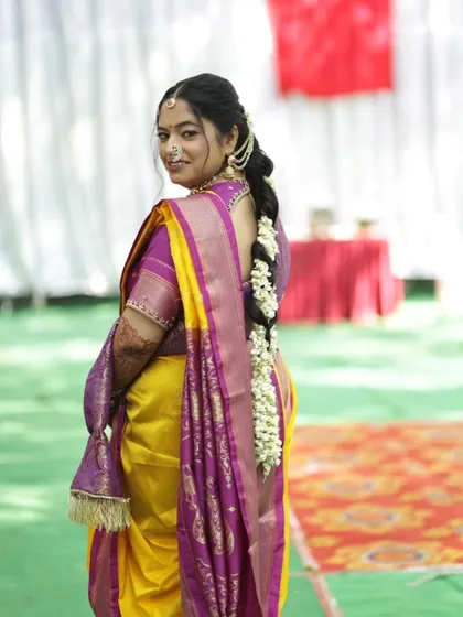 The back view of this bride showcases the traditional braided hairstyle, adorned with fresh flowers, which is a key element of the Maharashtrian bridal look. I handle hairstyling to ensure it perfectly complements the makeup and outfit.