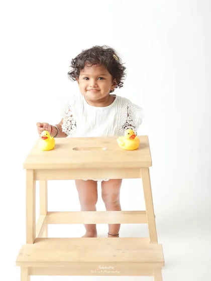 A cheerful smile and two little rubber ducks. A simple, happy portrait of a toddler enjoying her studio session.