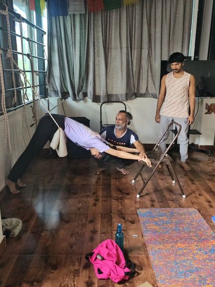 A student uses a chair and wall ropes to explore a variation of Downward-Facing Dog. This supported version helps build strength and awareness without straining the wrists or shoulders.