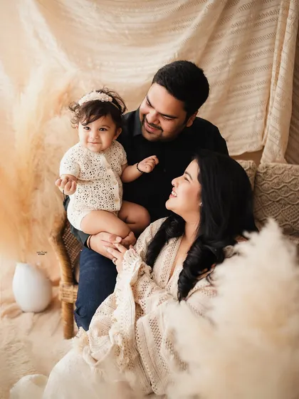 The complete family, happy and relaxed in a warm, neutral-toned studio setup.