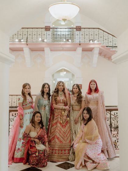 The bride stands with her bridesmaids, a beautiful portrait of friendship and support. The grand staircase of the Taj Mahal Palace provides a regal setting.