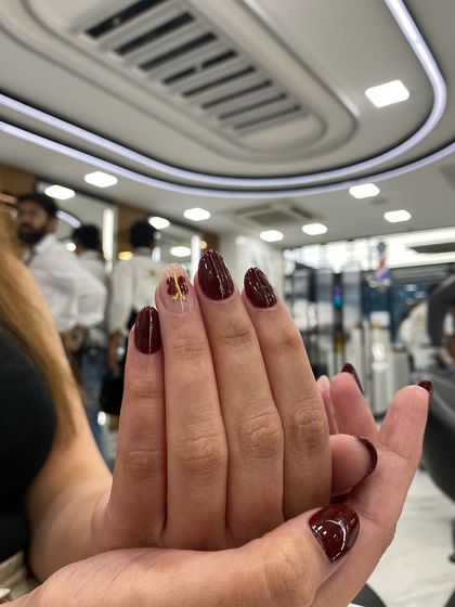 A deep maroon set with a delicate gold butterfly accent on one nail, perfect for an elegant and understated look.