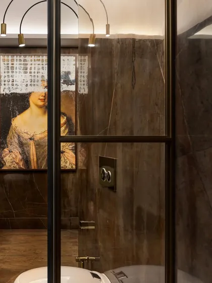 A peek into the Victorian-inspired bathroom, showing the reflection of the unique artwork. The rich brown marble and brass details whisper luxury and refinement.
