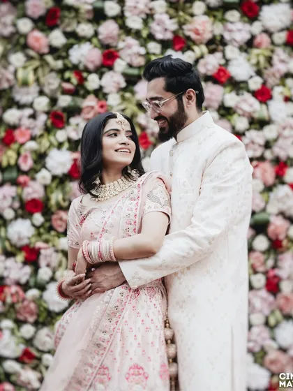 An elegant couple portrait set against a beautiful wall of flowers. I guide my couples into comfortable poses that still feel natural, capturing the grace of their traditional outfits and the joy of the moment.
