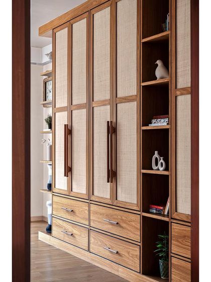 A different angle of the veneer and rattan wardrobe, showing how the open shelving breaks up the solid wall of storage and provides a space for personal decor.