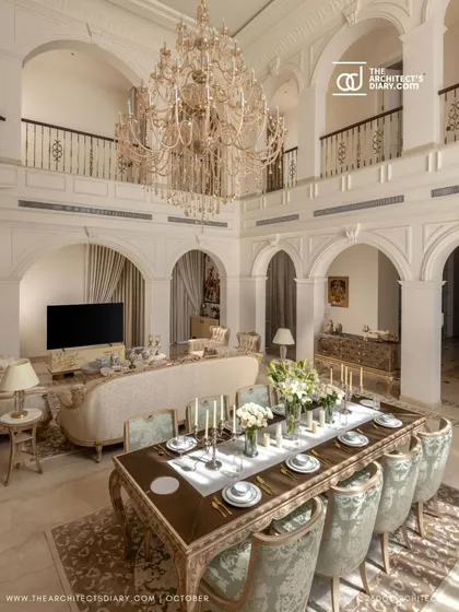 The double-height living and dining space in The Ivory Royale is a breathtaking example of neoclassical design. A massive chandelier hangs over the dining table, while arched galleries overlook the entire scene, creating a truly palatial feel.