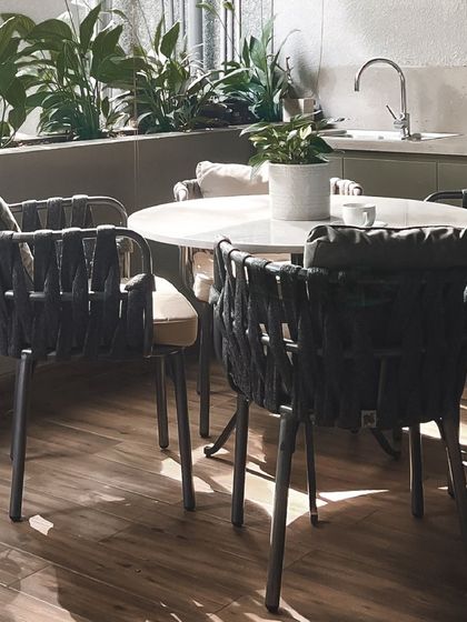A close-up of the woven outdoor chairs on the wooden deck, a perfect spot for a morning coffee.