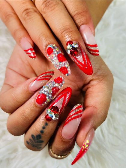 The ultimate festive nails. This look combines red French tips, glitter accents, and heavy 3D gem work for a style that is guaranteed to get noticed.