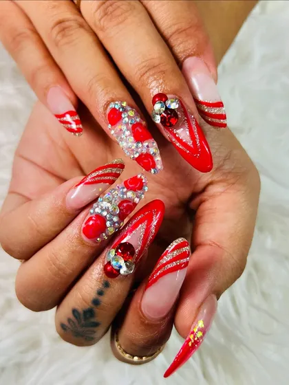 The ultimate festive nails. This look combines red French tips, glitter accents, and heavy 3D gem work for a style that is guaranteed to get noticed.