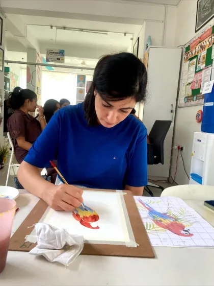 A student in our short-term course working on a detailed watercolor painting of a parrot. These courses allow you to tackle more complex and rewarding projects.