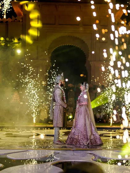 A couple stands amidst sparks and smoke on a beautifully designed stage. For 7 years, we've poured our souls into every detail to create flawless, heartfelt moments like this.