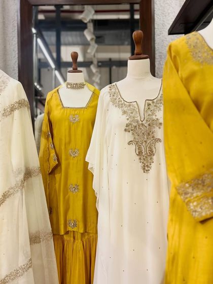 A display of elegant white and yellow outfits, showcasing the beauty of gold and silver embroidery.
