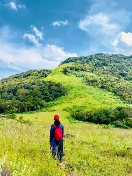A lone trekker walking towards the mountain, capturing the scale of the landscape.