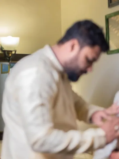 A candid, behind-the-scenes moment of the groom getting help with his outfit before the ceremony.